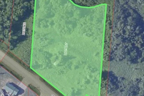 Aerial view shows a rural landscape with scattered houses and a winding stream. - 2.17 Acres Route 355, Sainte Rose