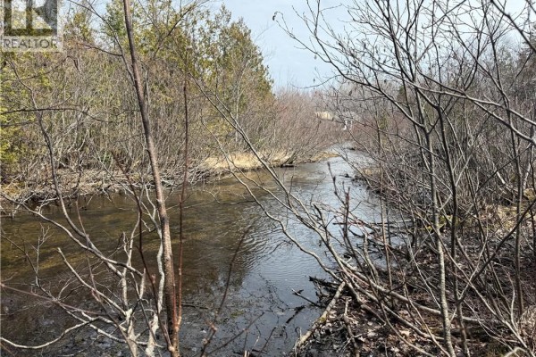 Aerial perspective of a property with a paved road, buildings, and natural wooded areas. - 2.17 Acres Route 355, Sainte Rose