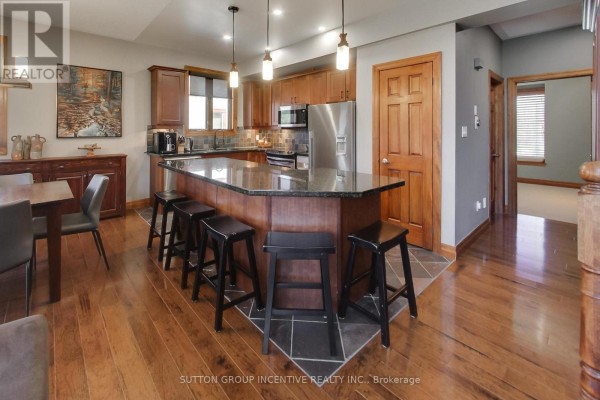 Kitchen island with granite countertops and dark stools, adjacent to dining area. - 20 - 224 Blueski George Crescent, Blue Mountains