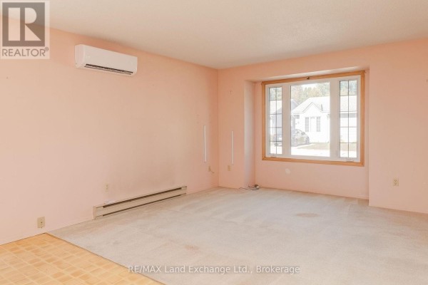Interior view of a living room with light pink walls, beige carpet, and a bay window overlooking the exterior. - 20 - 303 Waterloo Street, Saugeen Shores