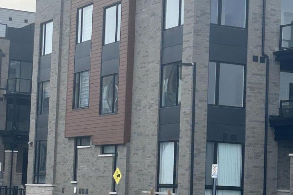 Close-up of a modern townhouse exterior with gray brick, black accents, and large windows. - 20 - 3175 Denison Street, Markham