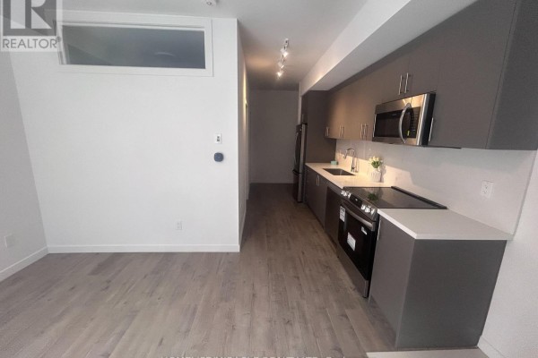 Compact kitchen with dark gray cabinets, stainless steel appliances, and light wood-look flooring. - 20 - 3175 Denison Street, Markham