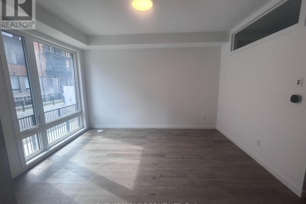 Living space with large windows offering a view of the exterior, white walls, and wood-look flooring. - 20 - 3175 Denison Street, Markham