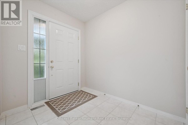 Interior front entryway with white door, glass sidelight, beige walls, and white tiled floor. - 20 - 941 Gordon Street, Guelph