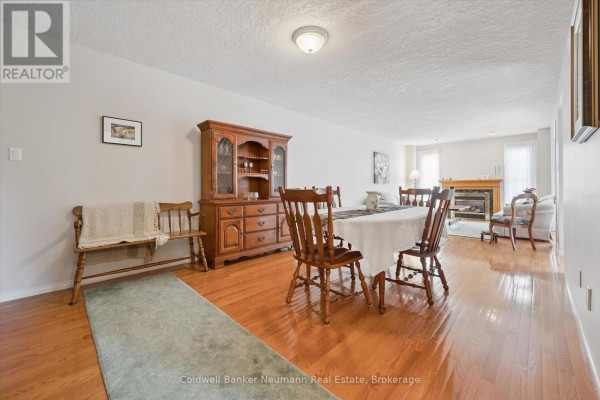 Open concept dining and living area with hardwood floors, wooden dining set, and fireplace. - 20 - 941 Gordon Street, Guelph