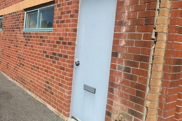 Close-up of a light blue metal door on a red brick wall with a mail slot. - 20 & 21 - 106 Saunders Road, Barrie