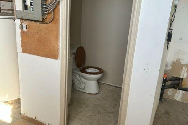 Small washroom with a white toilet and wood seat, visible through an open doorway. - 20 & 21 - 106 Saunders Road, Barrie
