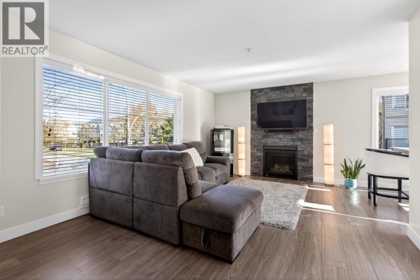 Living room with large windows, stone fireplace, and sectional sofa. - 20 2488 Pitt River Road, Port Coquitlam
