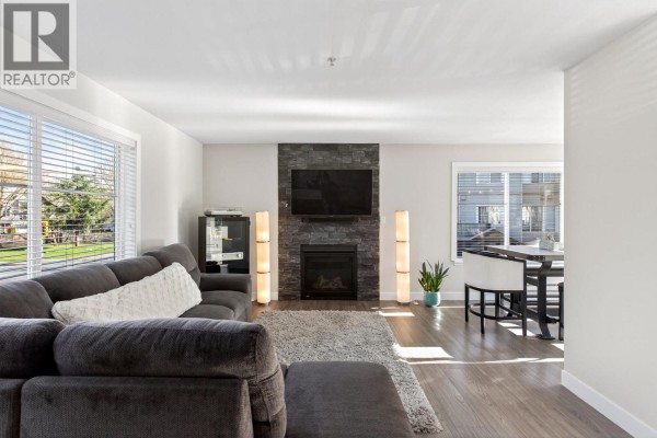 Another angle of living room featuring stone fireplace and dining area. - 20 2488 Pitt River Road, Port Coquitlam