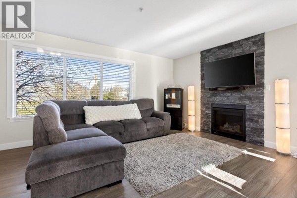 Cozy living room with sectional sofa, large window, and stone fireplace. - 20 2488 Pitt River Road, Port Coquitlam