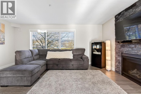 View of living room with sectional sofa, fireplace, and natural light from windows. - 20 2488 Pitt River Road, Port Coquitlam