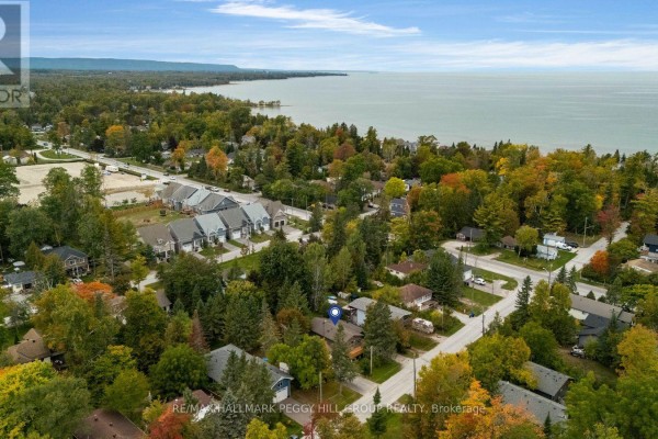 Aerial view of Wasaga Beach showing houses, trees, and a large body of water under a blue sky. - 20 61st Street S, Wasaga Beach