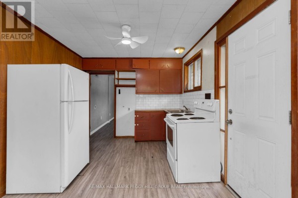 A kitchen with white appliances, red cabinets, white subway tile backsplash, and wood-paneled walls. - 20 61st Street S, Wasaga Beach