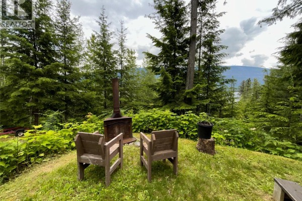 Outdoor seating area with two wooden chairs and a rustic metal wood stove. - 20-9000 Seymour Main Lot# 20, Seymour Arm