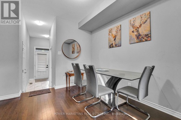 Dining area with a glass table, grey chairs, dark hardwood floors, and decorative deer artwork. - 20 Atop Lane, Ottawa