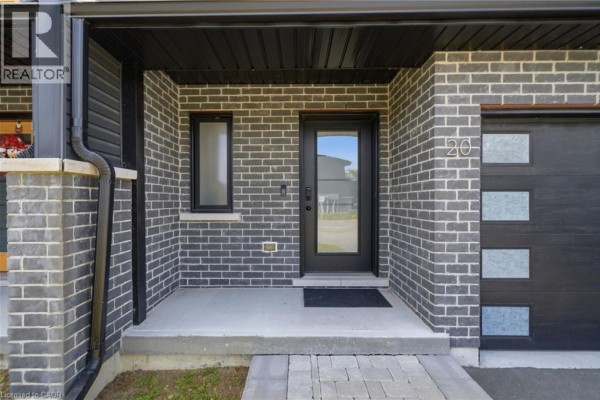 Close-up of the front entrance with a grey brick facade and a glass-paneled door. - 20 Brittany Lane, Quinte West