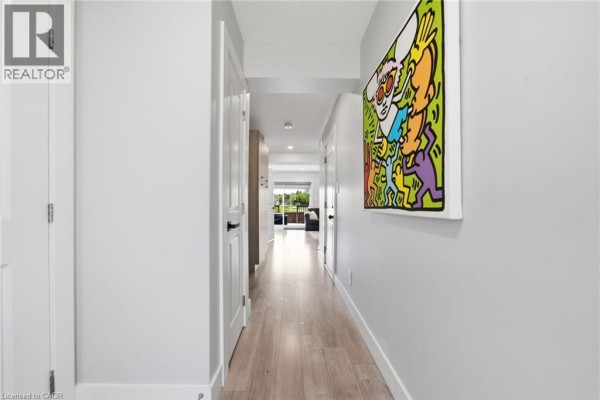 Interior hallway with light grey walls, light wood floors, and modern artwork. - 20 Brittany Lane, Quinte West