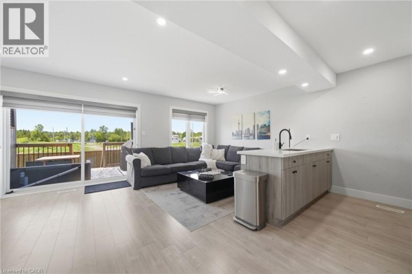 Open-concept living area with a sectional sofa, island kitchen, and large sliding doors. - 20 Brittany Lane, Quinte West
