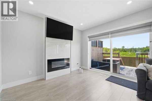 Living room features a modern fireplace with a mounted television and a sliding glass door. - 20 Brittany Lane, Quinte West