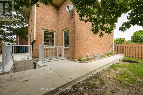 Concrete walkway around the side of a brick house leading to a backyard. - 20 Campkin Street, Brampton