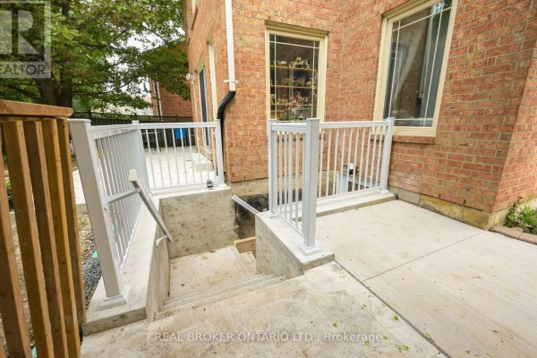 Concrete stairs with white railings leading down from a walkway to a basement entrance. - 20 Campkin Street, Brampton