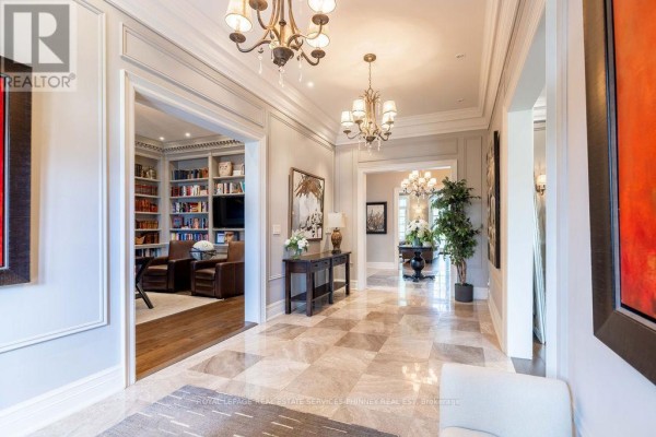Interior hallway with marble floors, doorways to rooms, and decorative chandeliers. - 20 Cluny Drive, Toronto