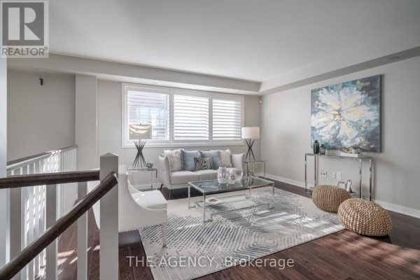 Living room with grey sofa, coffee table, and white accent chair. - 20 Cole Street, Toronto