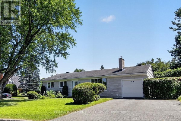 Side view of a bungalow with stone and vinyl siding, driveway, and garage. - 20 Cramer Drive, Ottawa