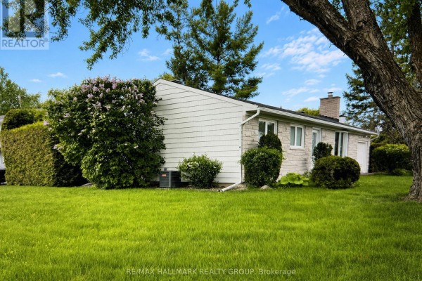 Rear side view of a bungalow with stone and white vinyl siding, and outdoor AC unit. - 20 Cramer Drive, Ottawa