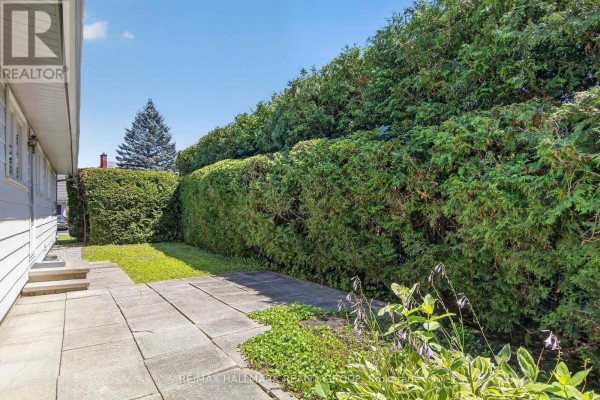 Backyard patio with large square concrete pavers and a pathway leading to a grass lawn. - 20 Cramer Drive, Ottawa