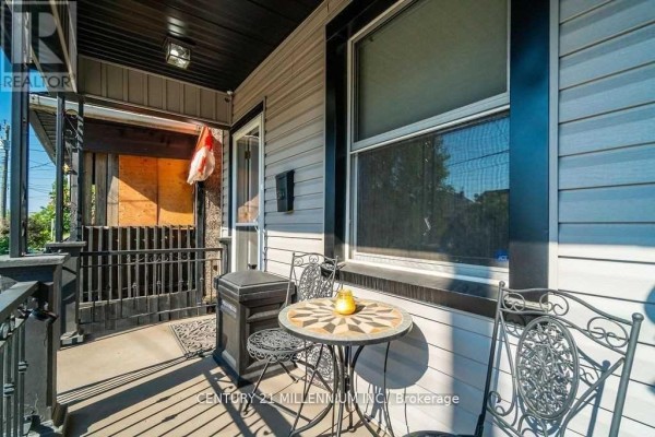 Front porch with two chairs, a round table, and a screened-in door. - 20 Dickson Street, Hamilton