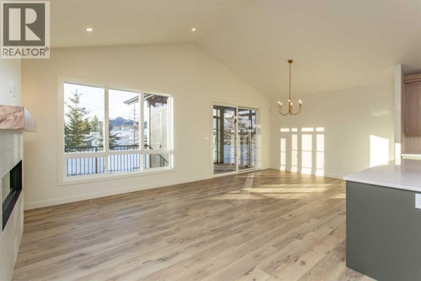 Spacious living room with vaulted ceiling, large windows, and light wood flooring. - 20 Emmett Crescent, Red Deer