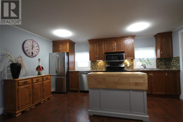Kitchen with dark wood cabinets, stainless steel appliances, and island. - 20 Evergreen Drive, Paradise