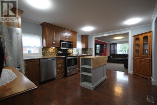 Kitchen with view into living room, dark wood cabinets, and island. - 20 Evergreen Drive, Paradise