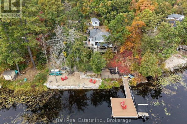 A wooden dock extends into the dark water, with seating and kayaks near the shore. - 20 Fire Route 93, Trent Lakes