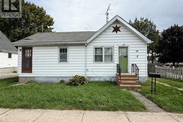 Front exterior view of a small white vinyl-sided house with a green door and a detached garage. - 20 First Street, Wallaceburg