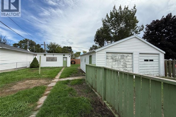Rear exterior view of a white house with a detached two-car garage and a wooden fence. - 20 First Street, Wallaceburg