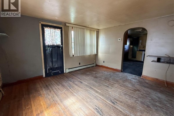 Living room with light brown walls, hardwood floors, a window with blinds, and an archway to another room. - 20 First Street, Wallaceburg