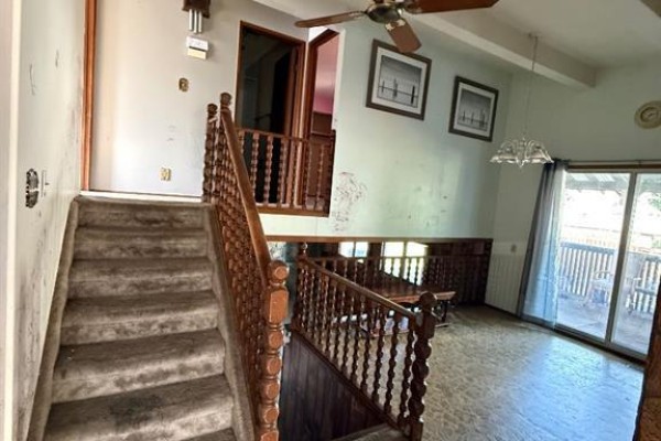 Interior view showing a staircase, entryway with a coat rack, and a stone accent wall. - 20 Goard Close, Red Deer