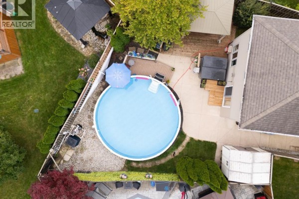 Aerial view of a circular above-ground pool with a blue umbrella and surrounding deck. - 20 Goldenrod Court, Chatham