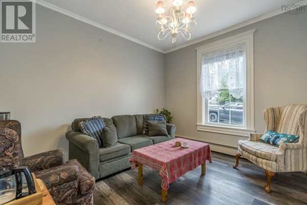 Living room with a green sofa, patterned armchair, plaid-covered coffee table, and gray walls. - 20 Gray Street, Windsor
