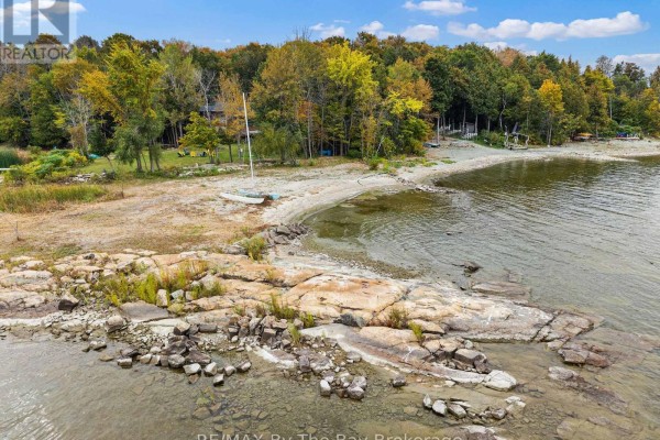 View of the island shoreline with rocks, sand, trees, and a sailboat on the beach. - 20 Island 404/quarry Island, Georgian Bay