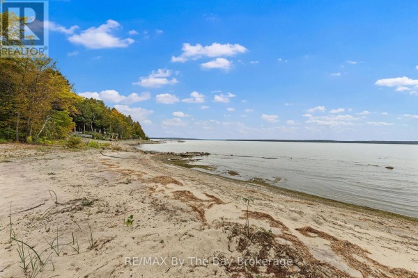 Sandy beach and calm water with trees and a clear blue sky on the horizon. - 20 Island 404/quarry Island, Georgian Bay