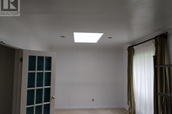 Room with white walls, a large skylight, recessed lighting, and sheer green curtains on the right. - 20 Johnson Street, Prince Edward County