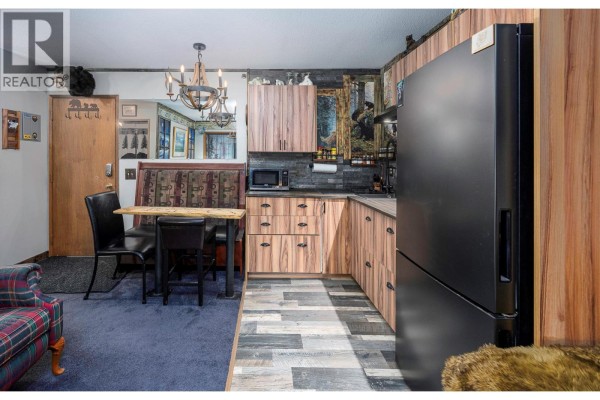 Kitchenette with wood-grain cabinets, a black refrigerator, and a built-in dining nook. - 20 Kettleview Road Unit# 305, Big White