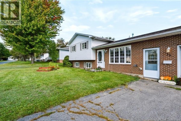 Side view of the house exterior showing lawn, trees, and driveway. - 20 Locke Street, Miramichi