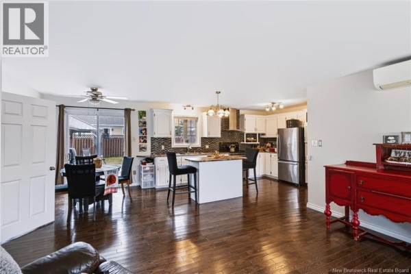 Open-concept living area with dark wood floors, white cabinets, and kitchen island. - 20 Locke Street, Miramichi