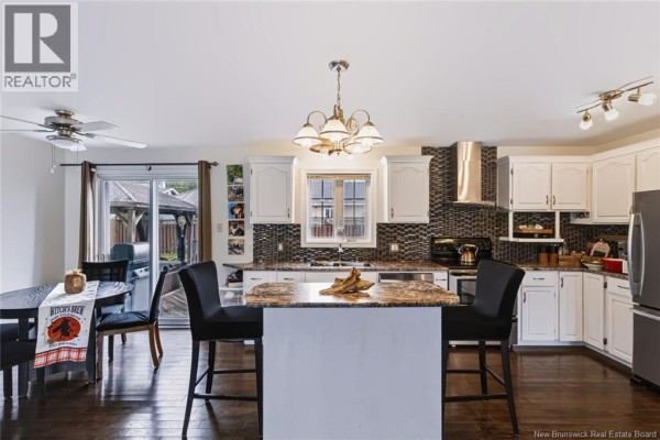 Kitchen with granite countertops, island with bar stools, and stainless steel appliances. - 20 Locke Street, Miramichi