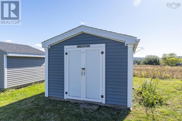 Small blue detached storage shed with double doors and white trim in grassy yard. - 20 Mackinnnon Court, Kentville