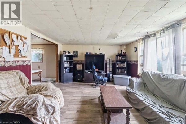 Living room with wood-paneled walls, a desk with a computer chair, and bookshelves. - 20 Mardon Avenue, Port Dover